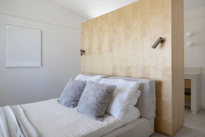 Dormitorio con diseño minimalista mediterráneo en Menorca, combinando tonos neutros, plantas de interior y mobiliario sostenible