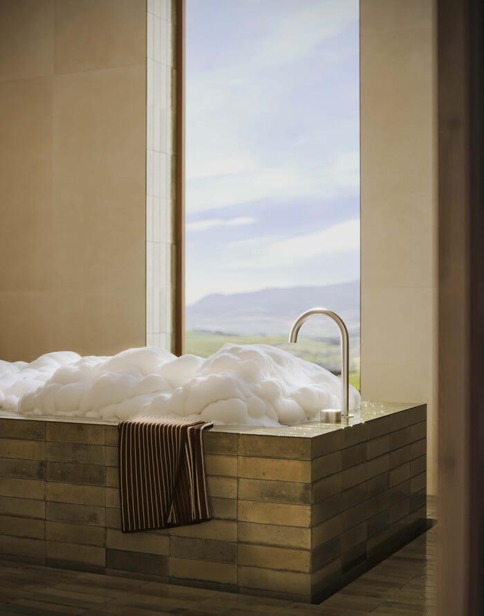 Bañera revestida con gres porcelánico Marazzi en tonos cálido con vistas a la naturaleza