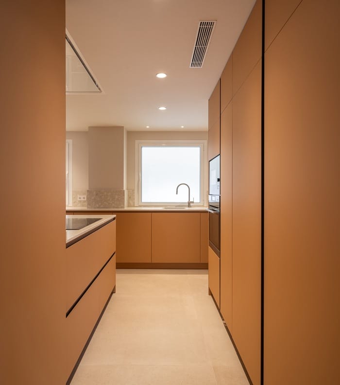 Cocina minimalista con mobiliario color terracota y luz natural, proyecto de JAO Arquitectura en Granada.
