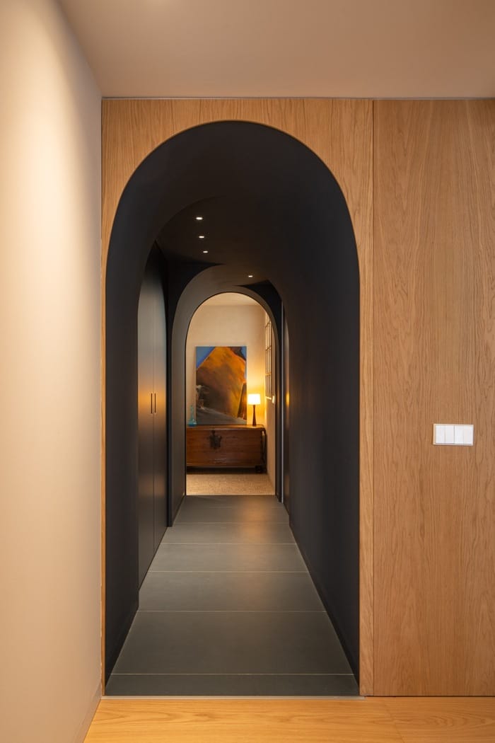 Vista del pasillo abovedado con paredes azul oscuro y luz cálida al fondo en la vivienda de JAO Arquitectura en Granada.